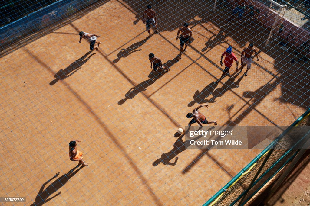 Overhead shot of a group of young men playing football on a dirt court