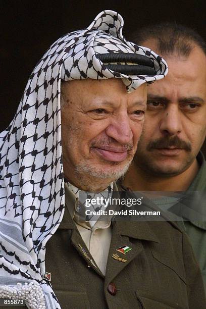 Bodyguard stands close to Palestinian President Yasser Arafat as he steps out of his office to bid farewell to a guest January 23, 2002 in the West...