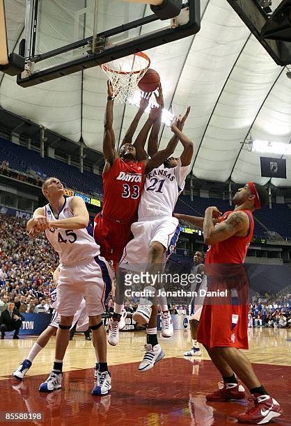 Chris Wright of the Dayton Flyers goes up for a rebound against Cole Aldrich and Markieff Morris of the Kansas Jayhawks during the second round of...