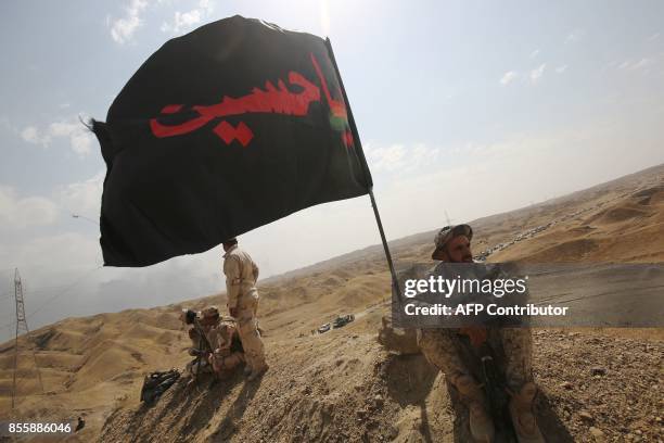 An Iraqi member of the Hashed al-Shaabi holds a flag from the Furqat al-Abbas brigades during a break from fighting against the Islamic State group...