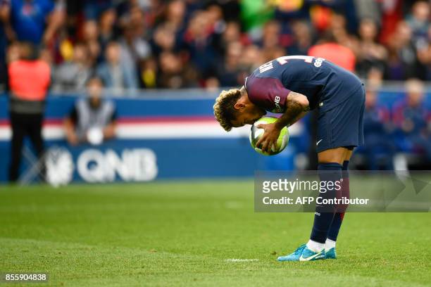 Paris Saint-Germain's Brazilian forward Neymar kisses the ball before shooting to score a penalty during the French L1 football match Paris...