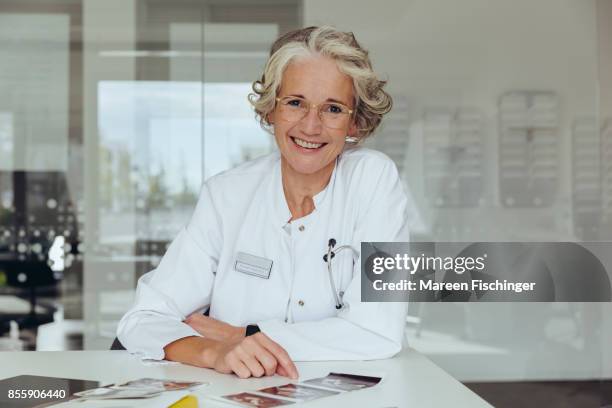 female gynaecologist looking up from ultrasound pictures of fetus - 20 week foetus stock pictures, royalty-free photos & images