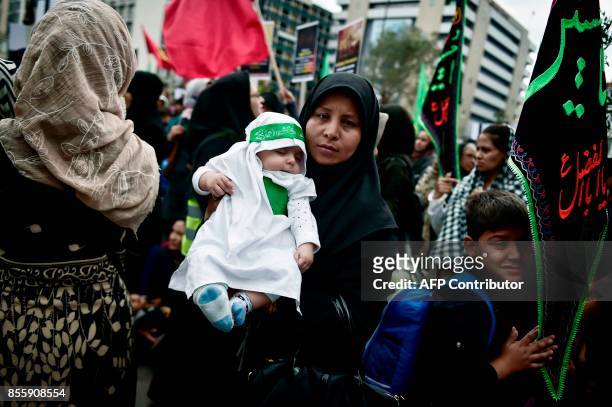 Shiite Muslim migrant holds a child in central Athens as they mark the Shiite religious holiday of Ashura on September 30, 2017. Ashura commemorates...
