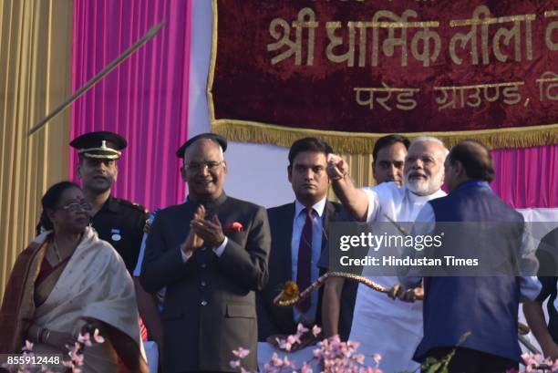 Prime Minister Narendra Modi uses bow and arrow during the Dussehra festival celebration organised by Shri Dharmik Leela Committee at Lal Quila...