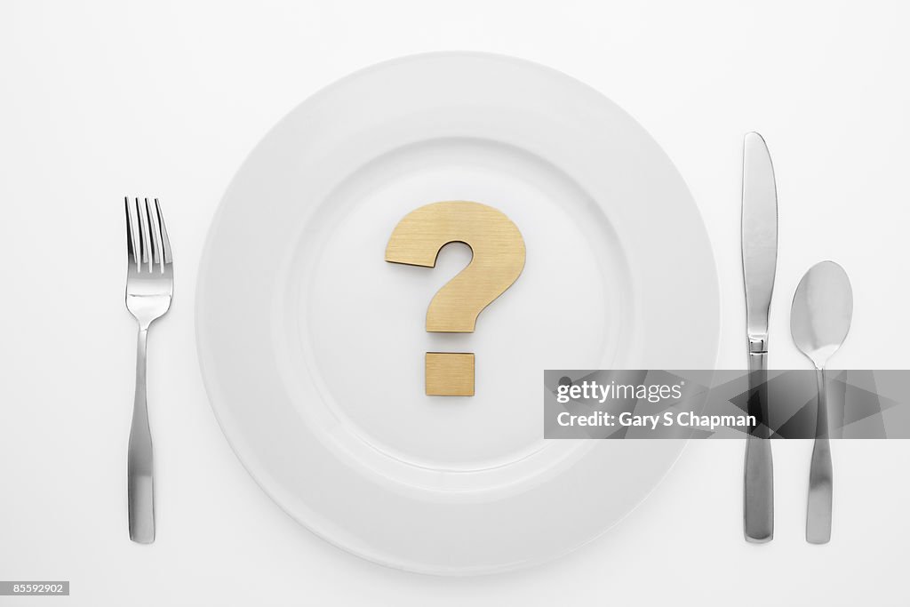 Brass question mark on white plate