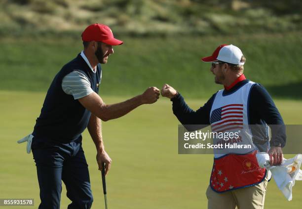 Dustin Johnson of the U.S. Team reacts to his putt with caddie John Wood during the Saturday morning foursomes matches during the third round of the...