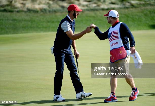 Dustin Johnson of the U.S. Team celebrates with caddie John Wood during the Saturday morning foursomes matches during the third round of the...