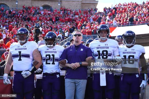 Tyler Lancaster, Justin Jackson, head coach Pat Fitzgerald, Clayton Thorson and Godwin Igwebuike of the Northwestern Wildcats lock arms before taking...