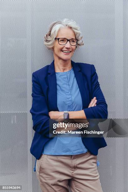 mature business woman leaning at wall outside office building - northern european descent stock pictures, royalty-free photos & images