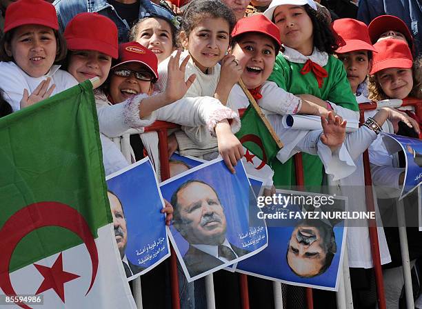 Algerian children carry national flags and posters of President Abdelaziz Bouteflika during an election campaign rally on March 25, 2009 in Bejaia,...