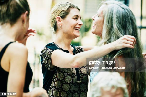 smiling friends embracing before summer dinner party - mid volwassen vrouw stockfoto's en -beelden
