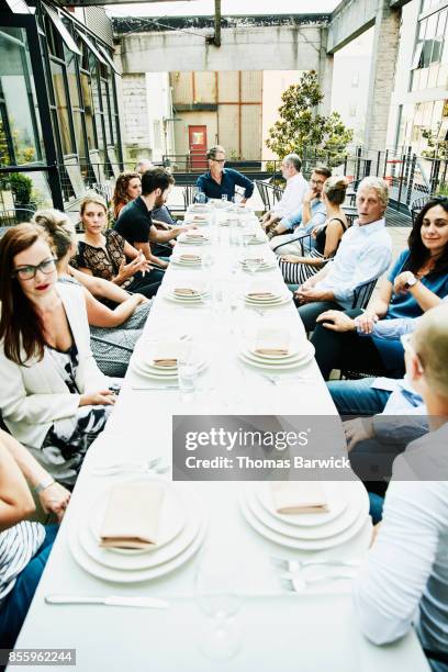 view down long table of group of friends seated for celebration meal on outdoor patio - long table stockfoto's en -beelden