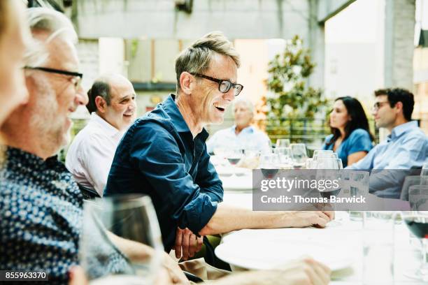 laughing friends sharing celebration dinner on restaurant patio - patio table stock pictures, royalty-free photos & images