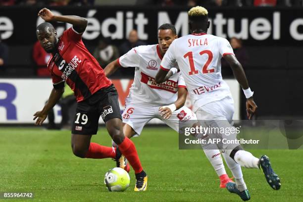 Guingamp's French midfielder Yannis Salibur vies with Toulouse's French defender Christopher Jullien and Toulouse's Guinean defender Issiaga Sylla...