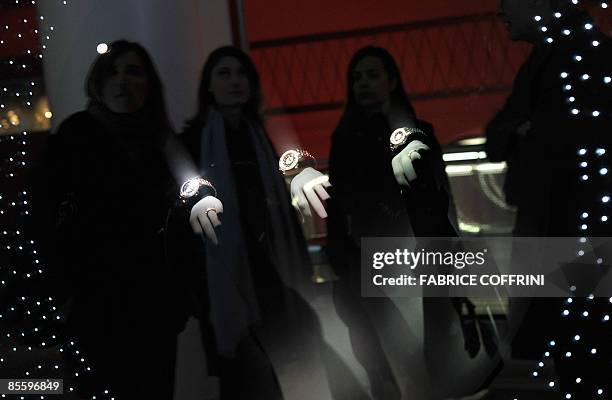 Visitors are seen reflected by a showcase displaying watches at the Dior booth during the press day at the Baselworld 2009 watch and jewellery show...