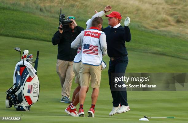 Charley Hoffman of the U.S. Team reacts after chipping in for birdie with caddies Brett Waldman and Joe Greiner on the 17th hole during the afternoon...