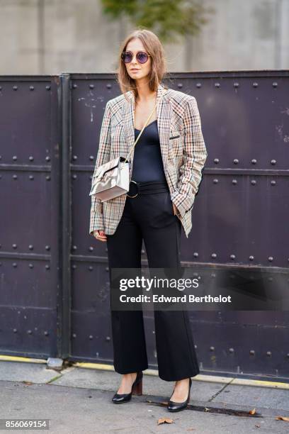 Guest wears a tartan jacket, a black top, black flare pants, outside Mugler, during Paris Fashion Week Womenswear Spring/Summer 2018, on September...