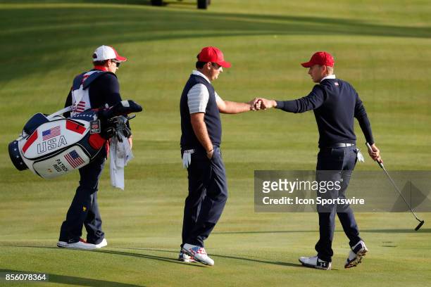 Golfer Patrick Reed and Jordan Spieth fist bump on the 4th hole during the third round of the Presidents Cup at Liberty National Golf Club on...