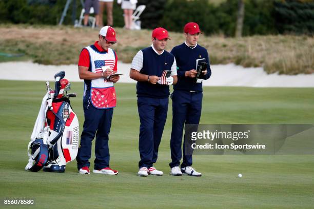 Golfers Patrick Reed and Jordan Spieth look at their yardage books on the 6th hole during the third round of the Presidents Cup at Liberty National...