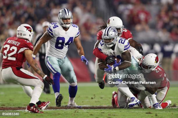 Running back Ezekiel Elliott of the Dallas Cowboys is tackled by outside linebacker Markus Golden and cornerback Justin Bethel of the Arizona...