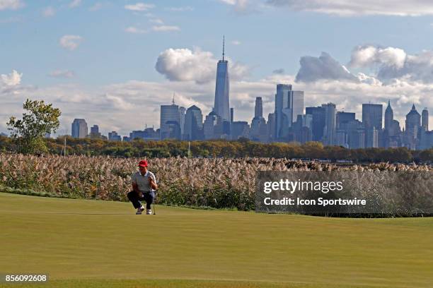 Golfer Patrick Reed putts on the 10th hole with the New York city skyline in the background during the third round of the Presidents Cup at Liberty...