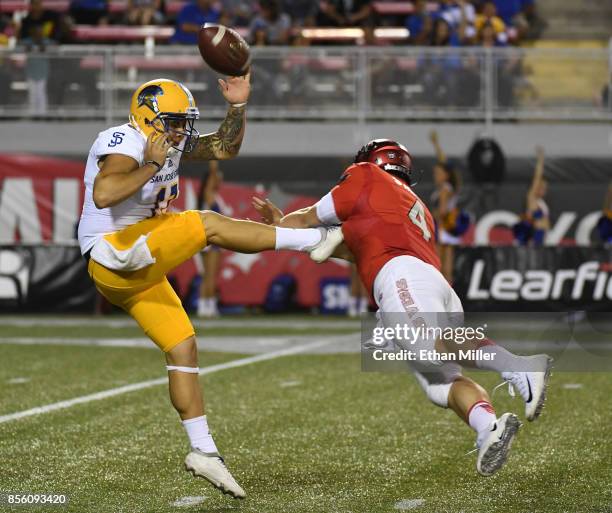 Quarterback Johnny Stanton of the UNLV Rebels blocks a punt by punter Michael Carrizosa of the San Jose State Spartans during their game at Sam Boyd...