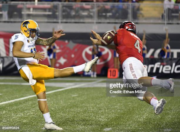 Quarterback Johnny Stanton of the UNLV Rebels blocks a punt by punter Michael Carrizosa of the San Jose State Spartans during their game at Sam Boyd...