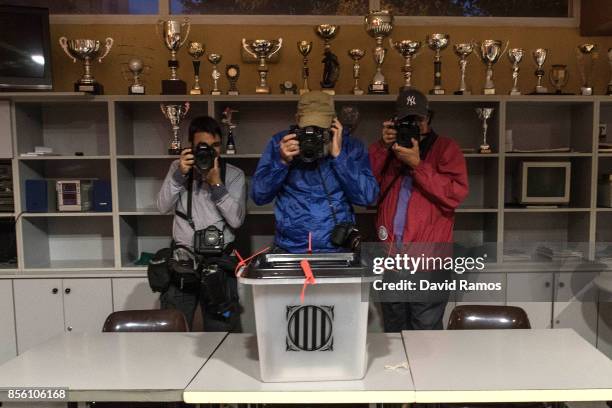 Photojournanlists take pictures of a ballot box at a polling station before the opening as the Catalan Government holds a referendum vote on October...