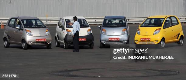 India-company-auto-Tata-Nano,SCENE by Phil Hazlewood A Tata Motors employee guides a colleague as he parks a Nano car ahead of a test drive session...