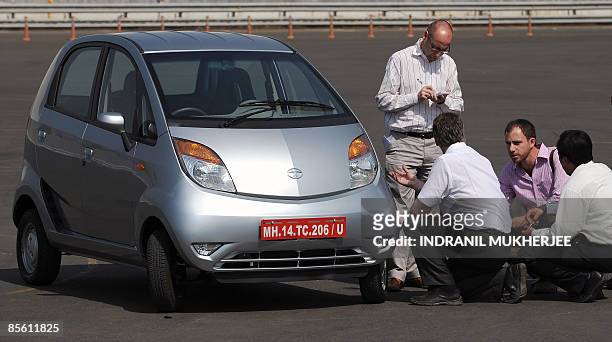 India-company-auto-Tata-Nano,SCENE by Phil Hazlewood Foreign journalists take notes as they inspect the Nano car on a track during a test drive...