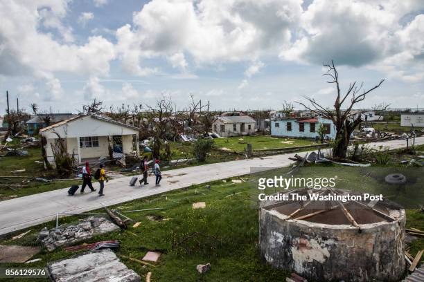 Peter Cuffy and his wife Jenita Cuffy walk behind a Red Cross crew as they look at the damages on the island of Barbuda in the aftermath of Hurricane...