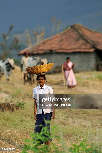 Young Indian villager looks up as she walks towards her home in the village of Purushwadi some 140 miles east of Mumbai on March 14, 2009. Inflation...