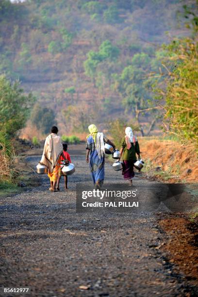 Indian villagers carry vessels as they walk towards a water handpump in the village of Purushwadi some 140 miles east of Mumbai on March 14, 2009....