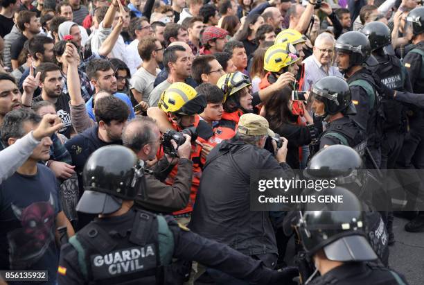 Firemen hold the people in front of Spanish Guardia Civil officers outside a polling station in San Julia de Ramis, on October 1 on the day of a...