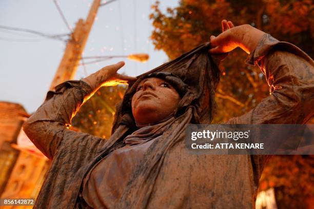 An Iranian Shiite Muslim woman stands next to a bonfire after rubbing mud on her body during the 'Kharrah Mali' ritual to mark the Ashura religious...