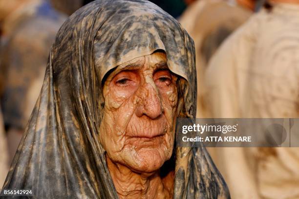 An Iranian Shiite Muslim woman looks on after rubbing mud on her body during the 'Kharrah Mali' ritual to mark the Ashura religious ceremony in the...