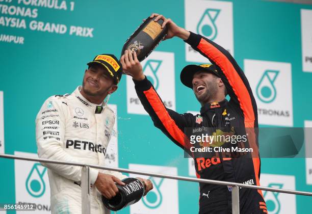 Third place finisher Daniel Ricciardo of Australia and Red Bull Racing celebrates with second place finisher Lewis Hamilton of Great Britain and...