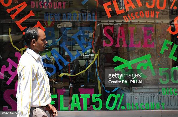 An Indian pedestrian walks past a shop window advertising discounted goods in Mumbai on March 26, 2009. Inflation in India edged closer to zero,...
