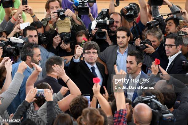 Catalonia President Carles Puigdemont holds up a red flower after failing to vote in the referendum because of the Spanish police closing his polling...