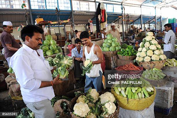 Vegetable sellers work at a market in Mumbai on March 26, 2009. Inflation in India edged closer to zero, official data showed, raising fears of...