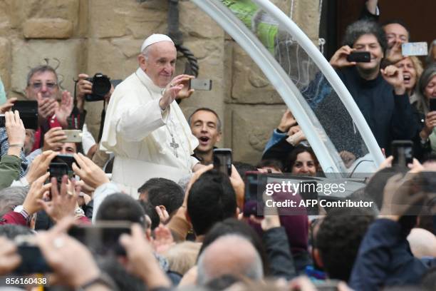 Pope Francis waves to the crowd from the popemobile as he arrives in Piazza Maggiore during a pastoral visit in Bologna on October 1, 2017. / AFP...