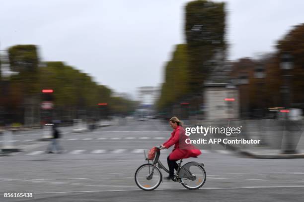 Woman cycles along the Place de la Concorde with the Arc de Triumph in the background during a "car free" day in Paris on October 1, 2017. Parisians...