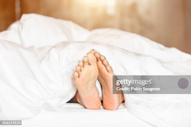 woman feet under white blanket side view. beautiful young woman feet with blue pedicure on the bed. - kid lying down stock pictures, royalty-free photos & images