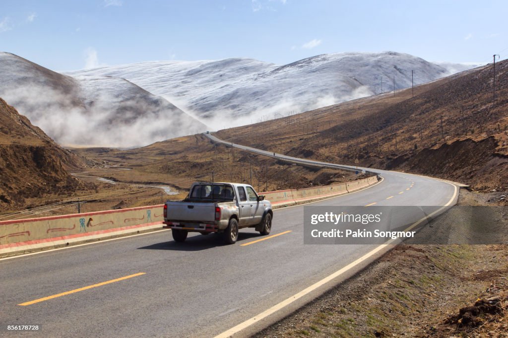 Pickup truck on the road, Beautiful winter road in Tibet under snow mountain Sichuan China