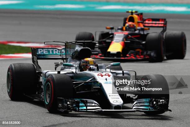 Lewis Hamilton of Great Britain driving the Mercedes AMG Petronas F1 Team Mercedes F1 WO8 leads Max Verstappen of the Netherlands driving the Red...