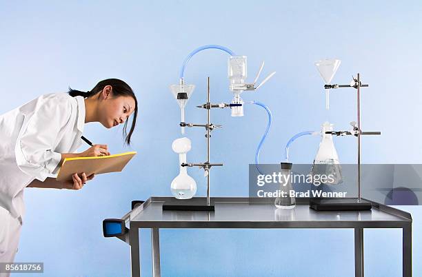 scientist takes notes on experiment - scientist standing next to table stock pictures, royalty-free photos & images