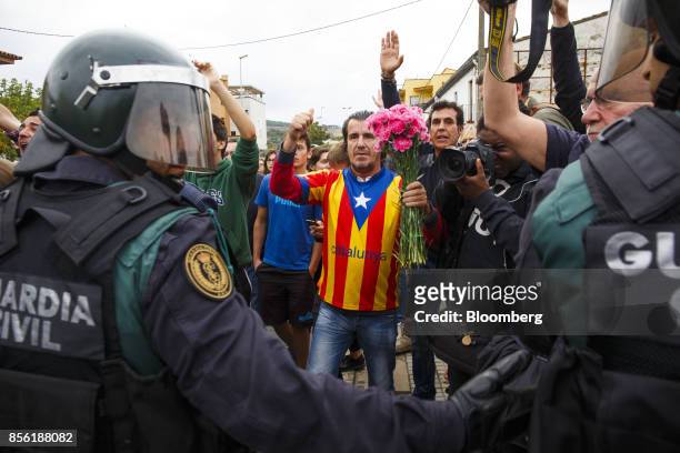 Civil Guard officers face a man wearing a pro-independence Catalan shirt and holding flowers outside a polling station used for the banned...