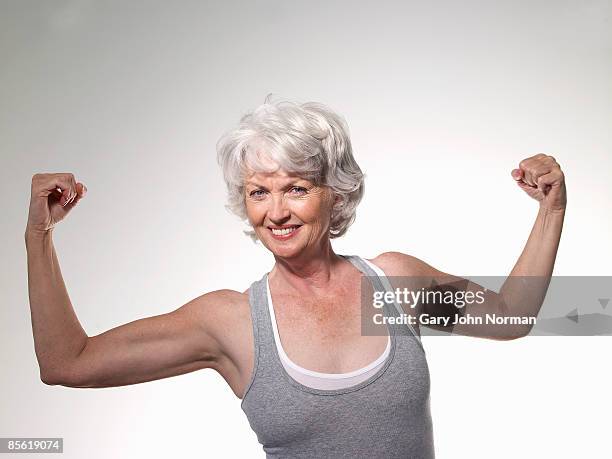 senior woman flexing muscles, smiling, portra - flexing arm stock-fotos und bilder