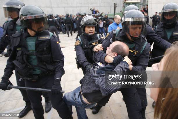 Spanish Guardia Civil guards drag a man outside a polling station in Sant Julia de Ramis, where Catalan president was supposed to vote, on October 1...