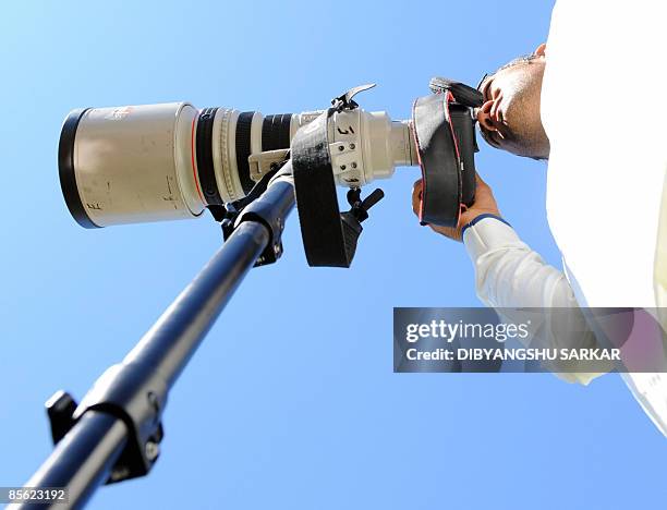 Indian cricket captain Mahendra Singh Dhoni tries his hand on a camera during the second day of the second Test match at the McLean Park in Napier on...